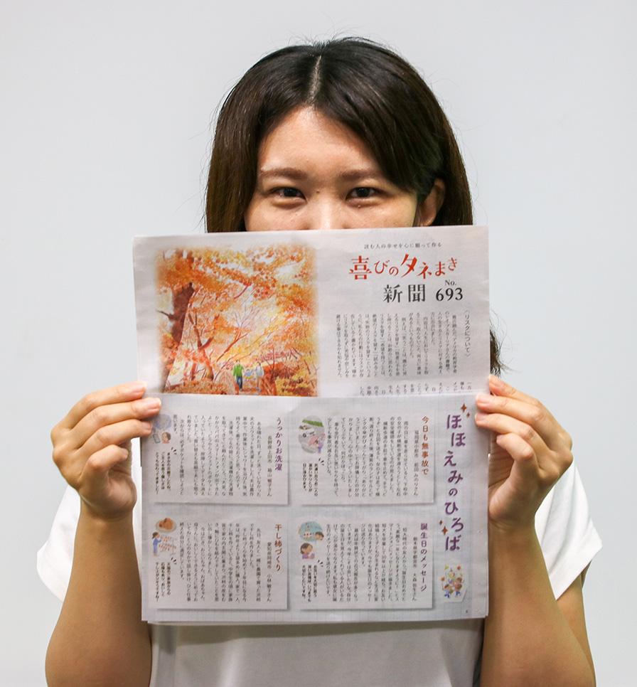 『喜びのタネまき新聞』最新号を持つ担当者S